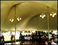 catered wedding in a large dome tent with a dance floor, lit with chandeliers