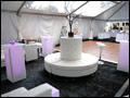wedding tent with white lounge furniture, light pillars and a dance floor