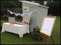 favors table at a LI farm wedding next to an old chicken coop, decorated with lace doilies, guest list is propped up on an easel